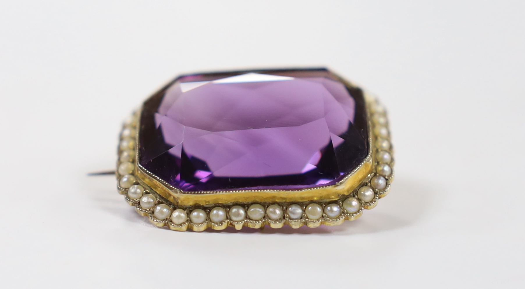 An Edwardian yellow metal mounted emerald cut amethyst and seed pearl cluster set brooch, 31mm, gross weight 11.9 grams.